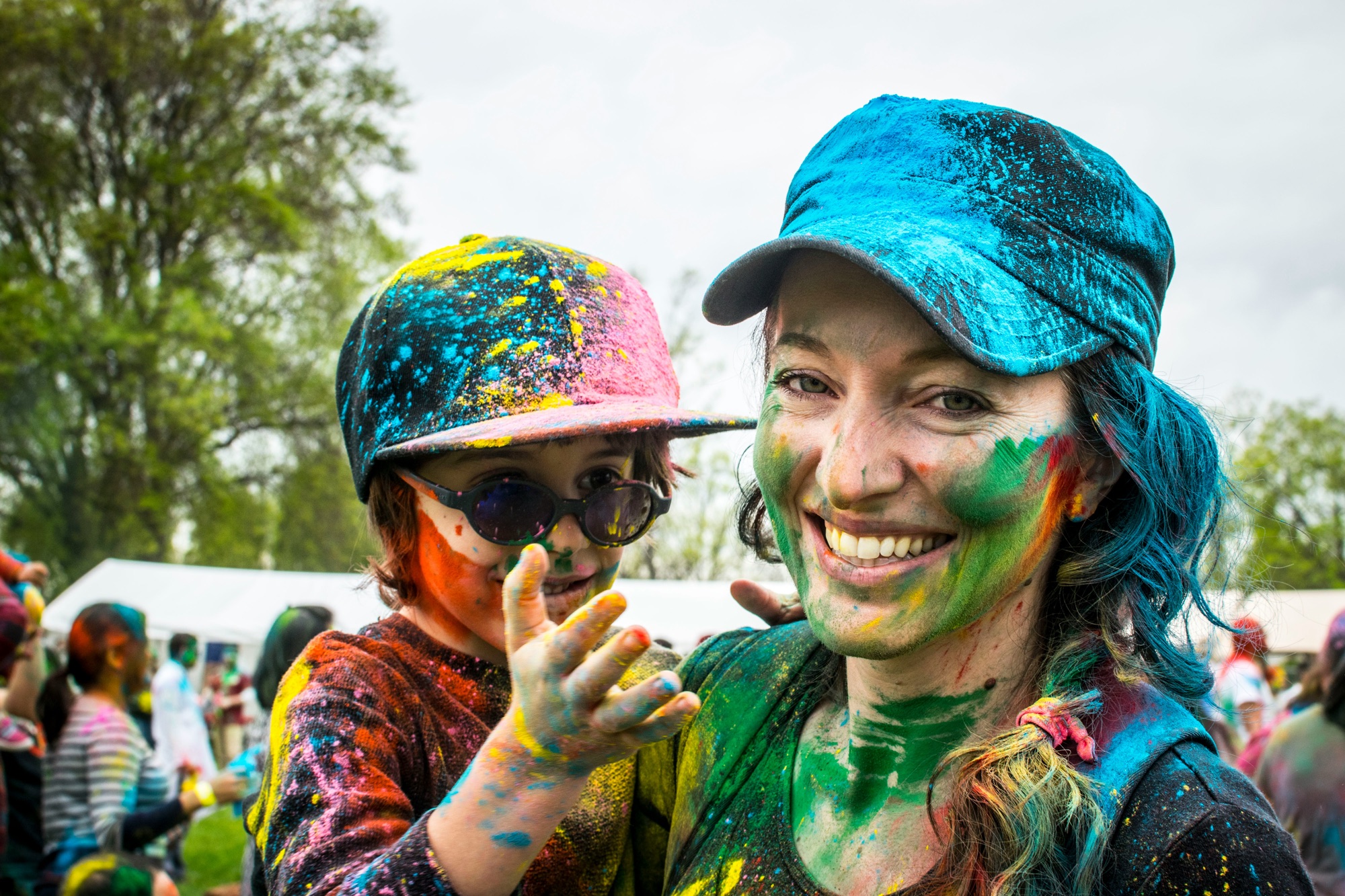 A woman and child covered in Holi colour powder, smiling at the camera